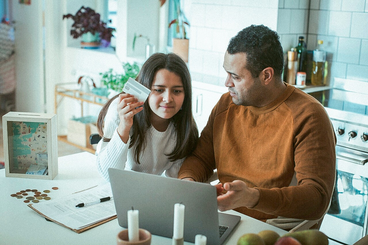 Vader met dochter aan tafel achter de laptop