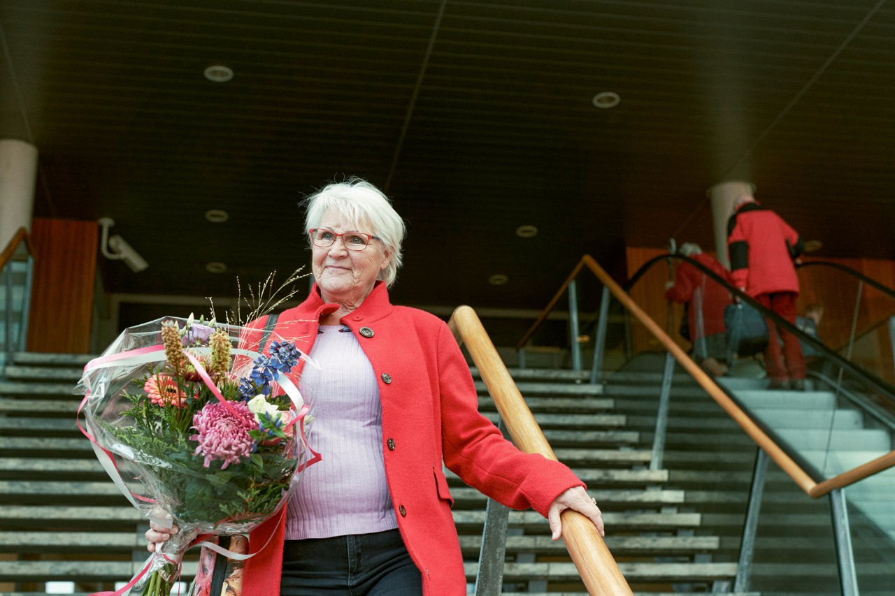 Oudere dame buiten met bloemen op een trap