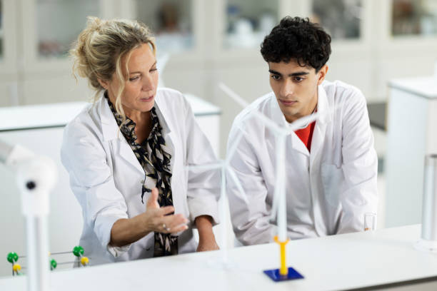 man en vrouw in witte jas bij schaalmodel windmolen