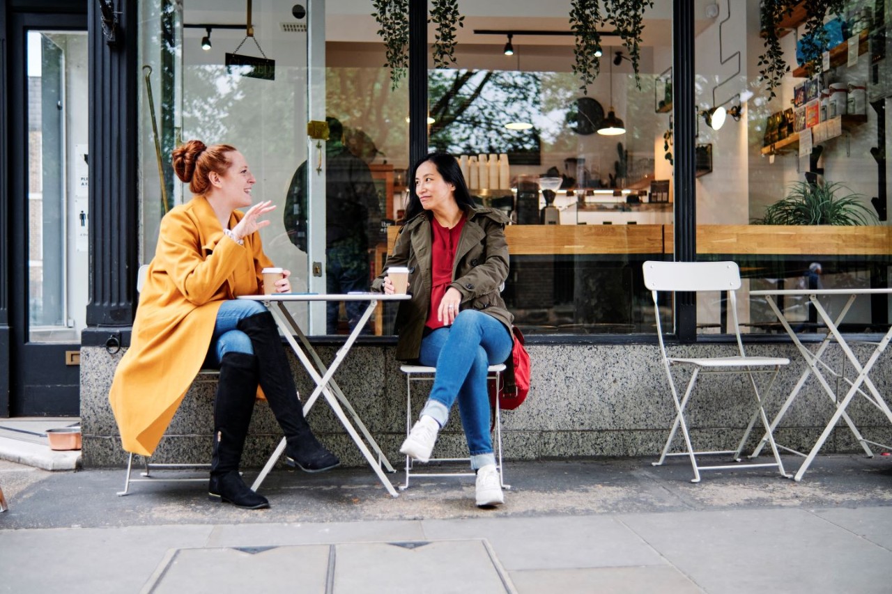 Twee vrouwen zitten op terras met koffie