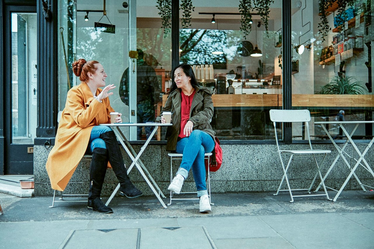 Twee vrouwen drinken koffie op een terras en praten met elkaar