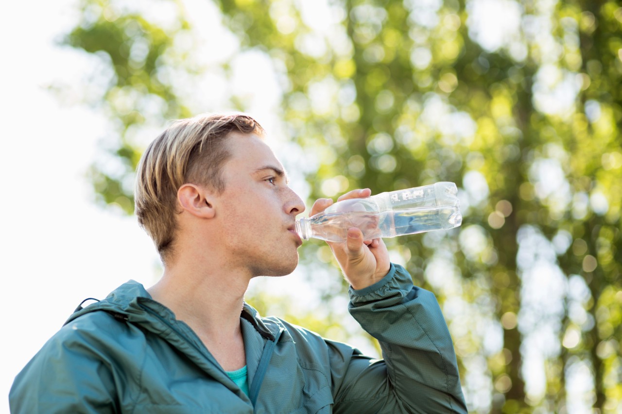 Buiten sportende man drinkt water