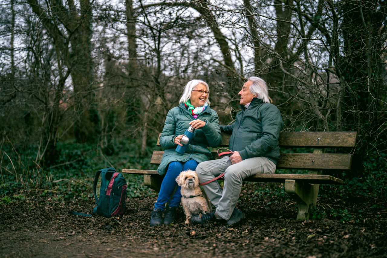 ouder stel zittend op bankje met hond