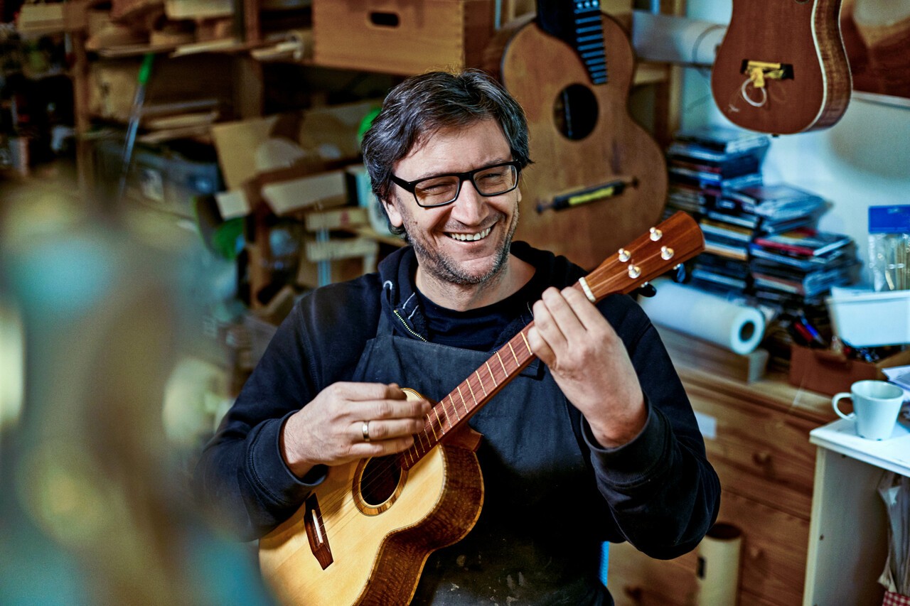 man met bril speelt vrolijk op gitaar