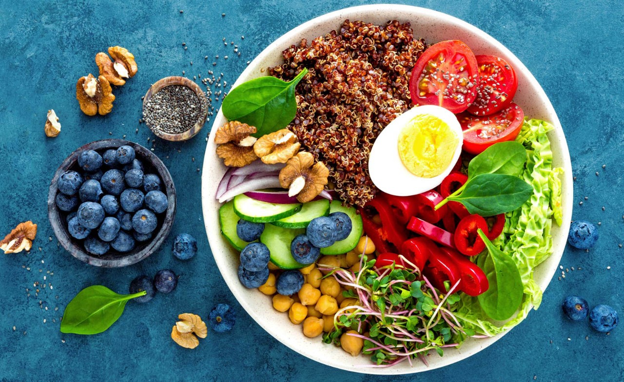 bakje blauwe bessen en schaal met gezonde salade en noten