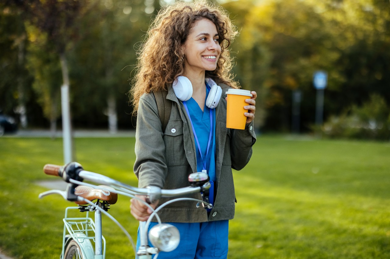 verpleegkundige met fiets en beker in park