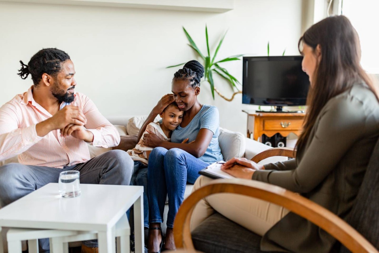 Gezin met kind op de bank met vrouw met schrijfblok en pen