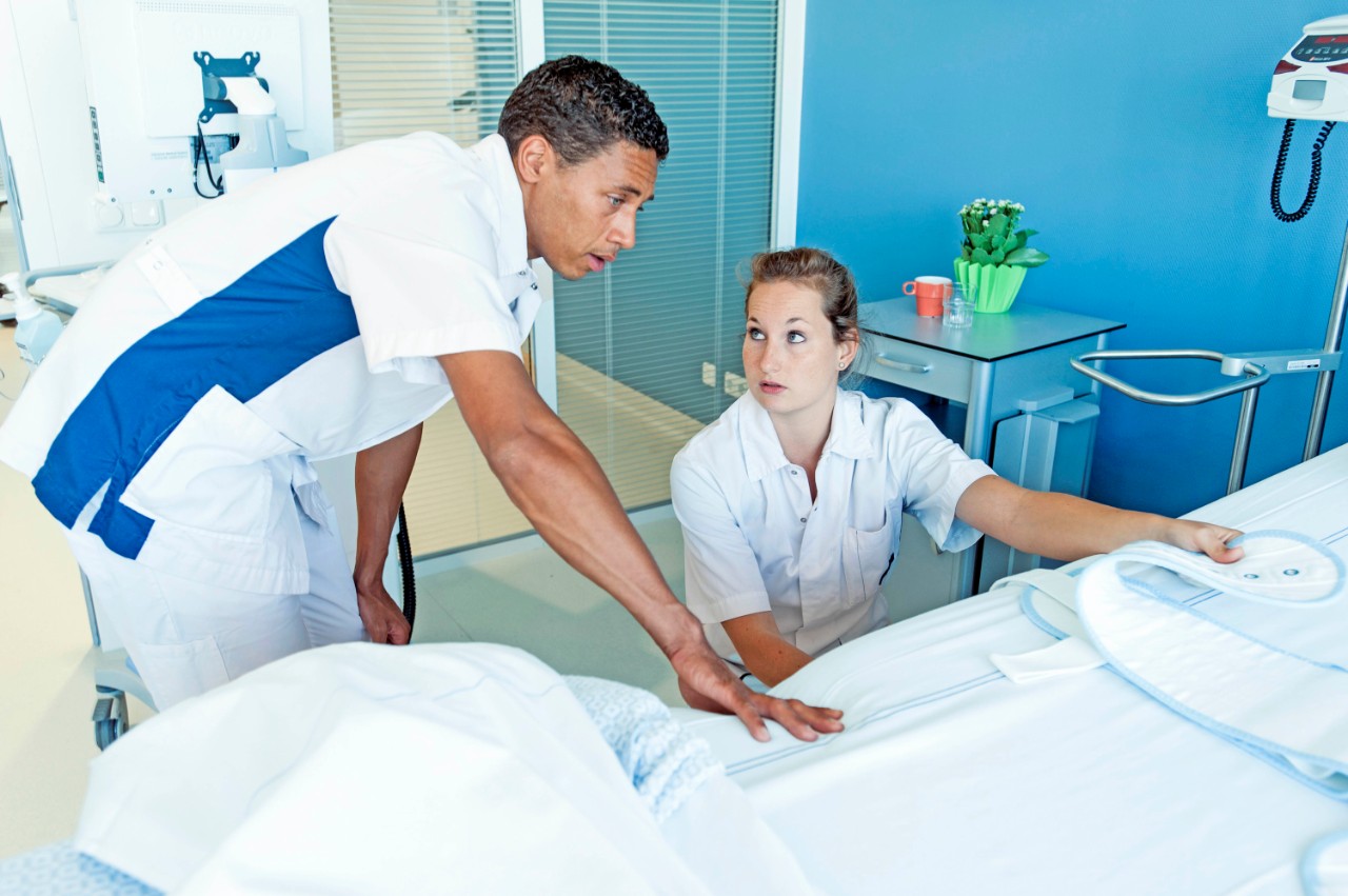 twee verpleegkundigen overleggen bij leeg ziekenhuisbed