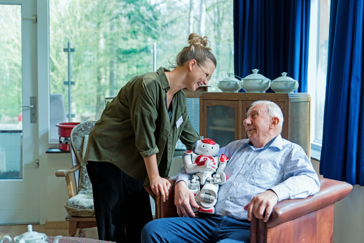 begeleider met bejaarde en robot