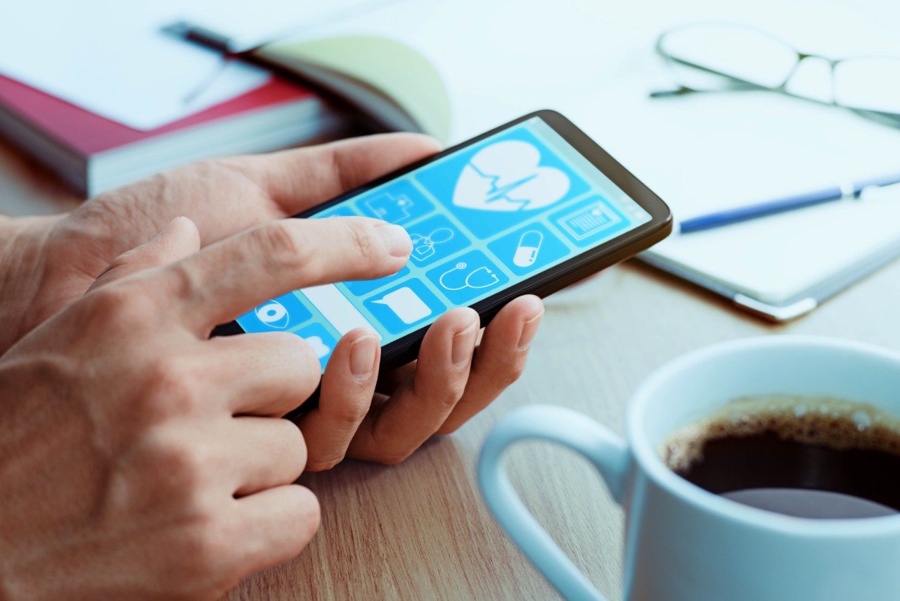 Closeup of male hands touching smartphone screen at table.