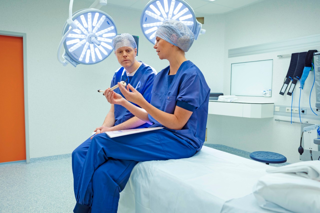 Verpleger thuiszorg houdt hand vast van iemand waarbij bloeddruk wordt gemeten