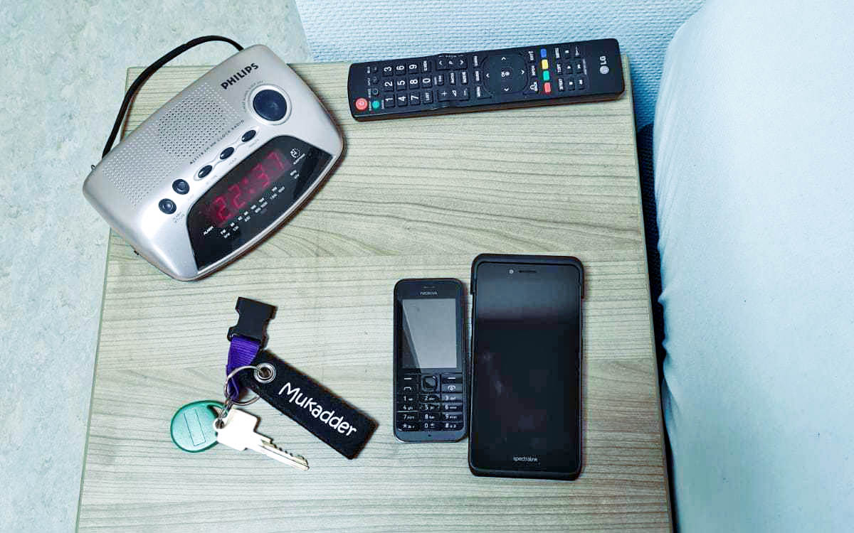 nachtkastje met telefoons, sleutels, afstandbediening en wekker