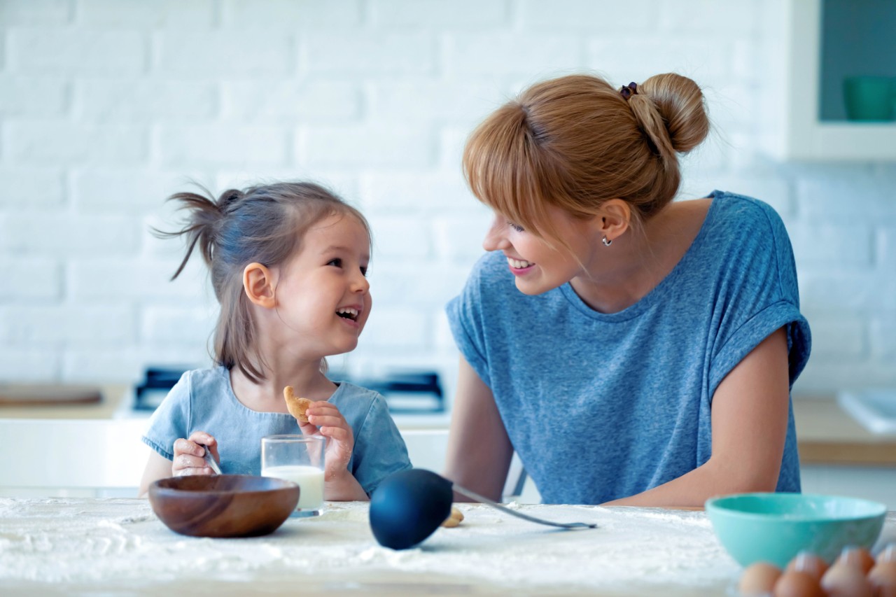 Vrouw met kind die eet en glas melk op tafel heeft