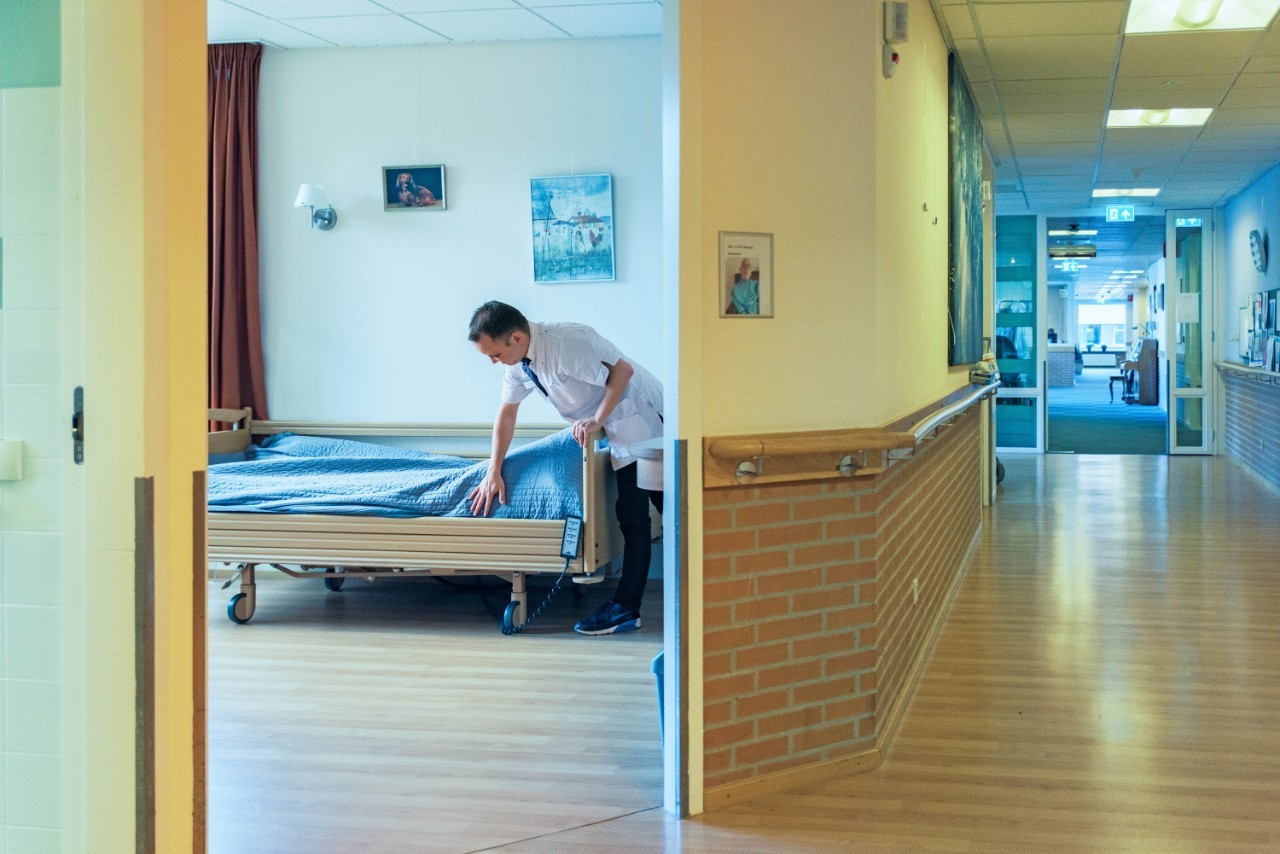 Verpleger dekt bed op in zorginstelling