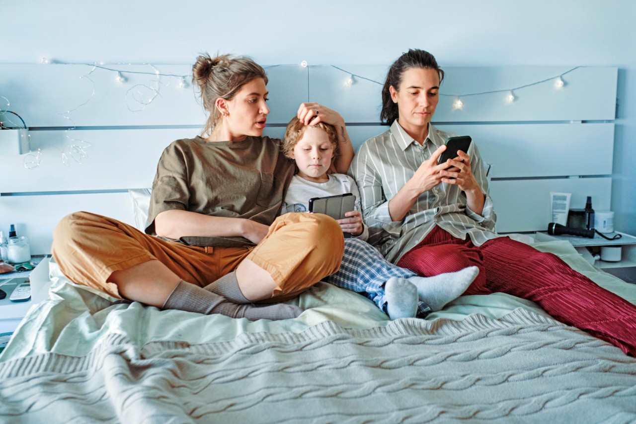 twee vrolijke vrouwen met kind in bed