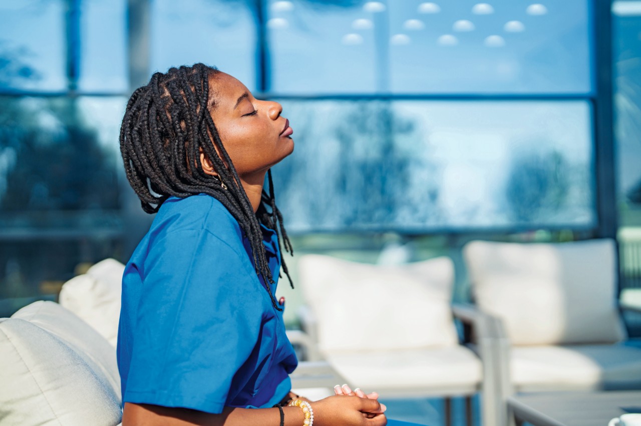 African Ethnicity female healthcare worker with blue scrubs working in medical clinic.