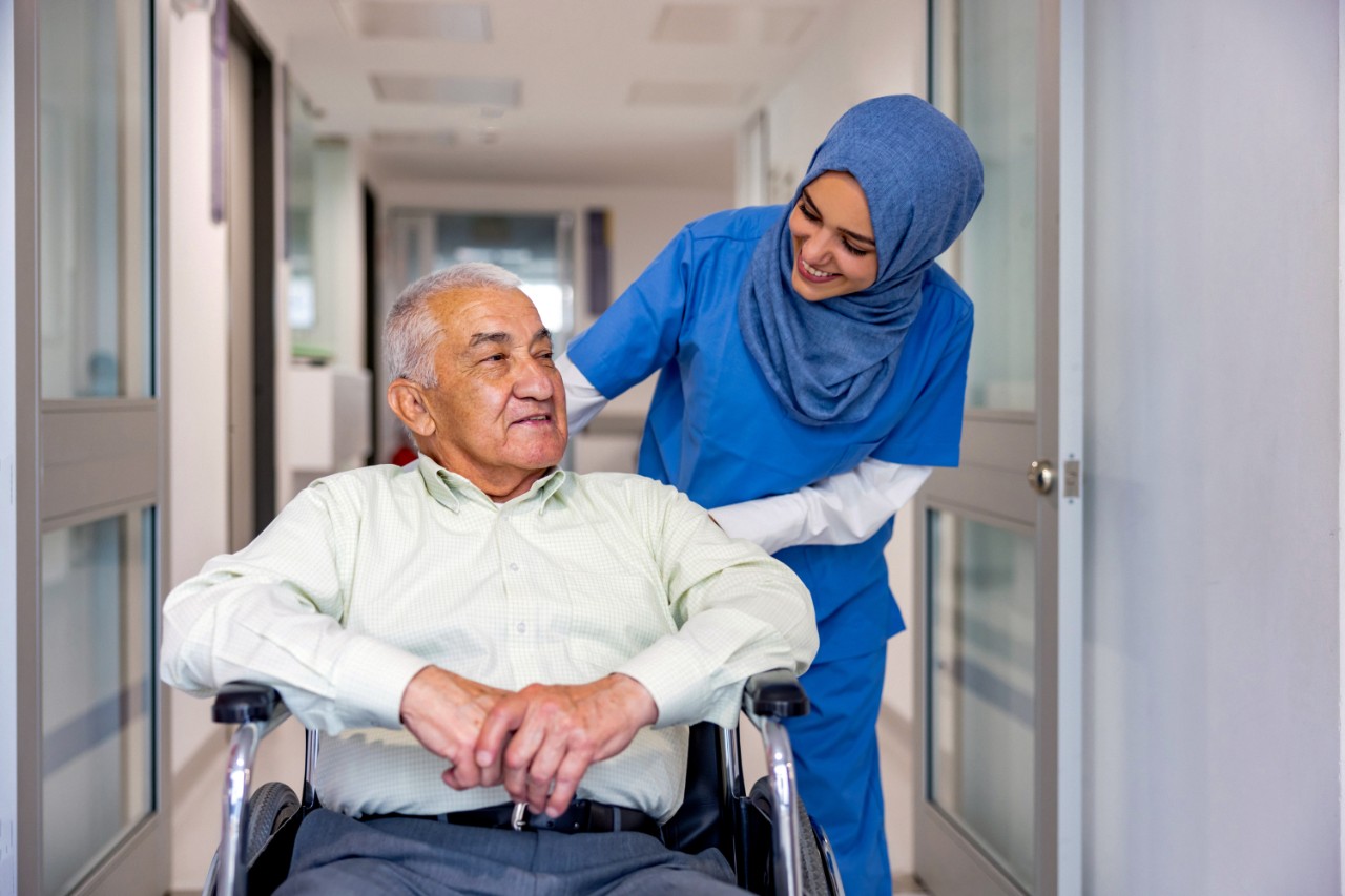 Oudere man in rolstoel met verpleegkundige.jpg
