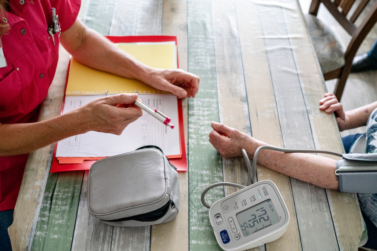 Verpleegkundige bloeddruk meten aan tafel close up