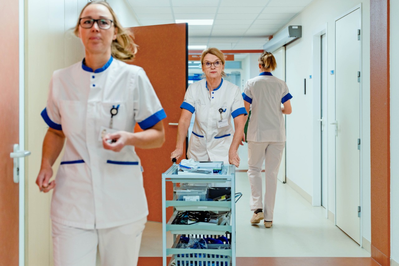 Drie verpleegsters lopen door de gangen van het ziekenhuis.