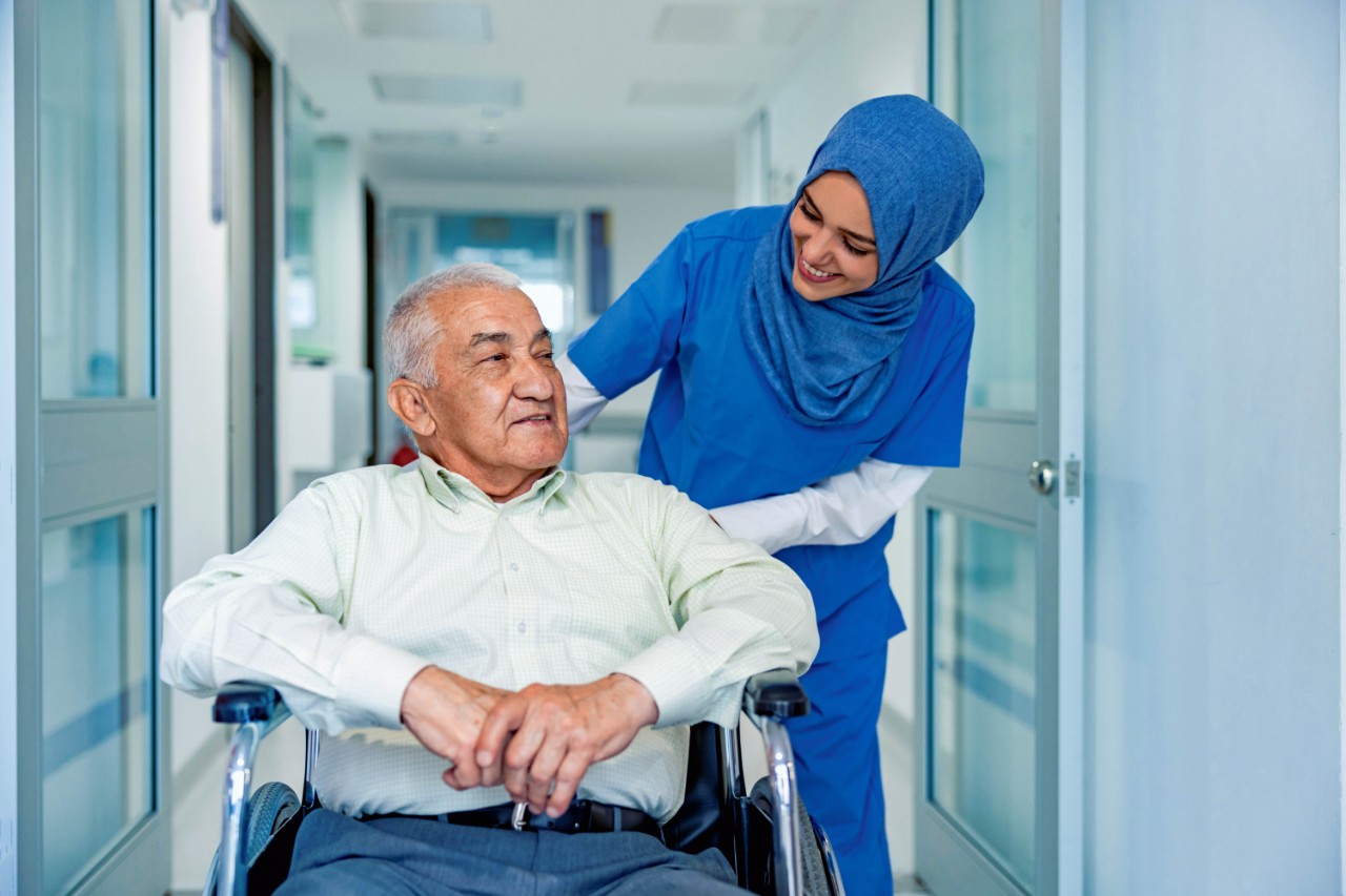 oudere man in rolstoel met verpleegkundige.