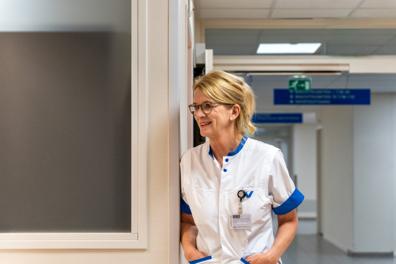 Lachende verpleegster leunt tegen muur